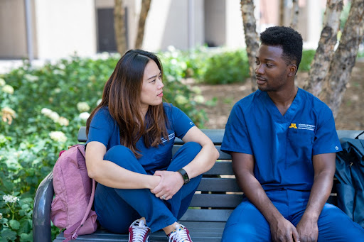 Two students talk on a bench outside of Moos Tower