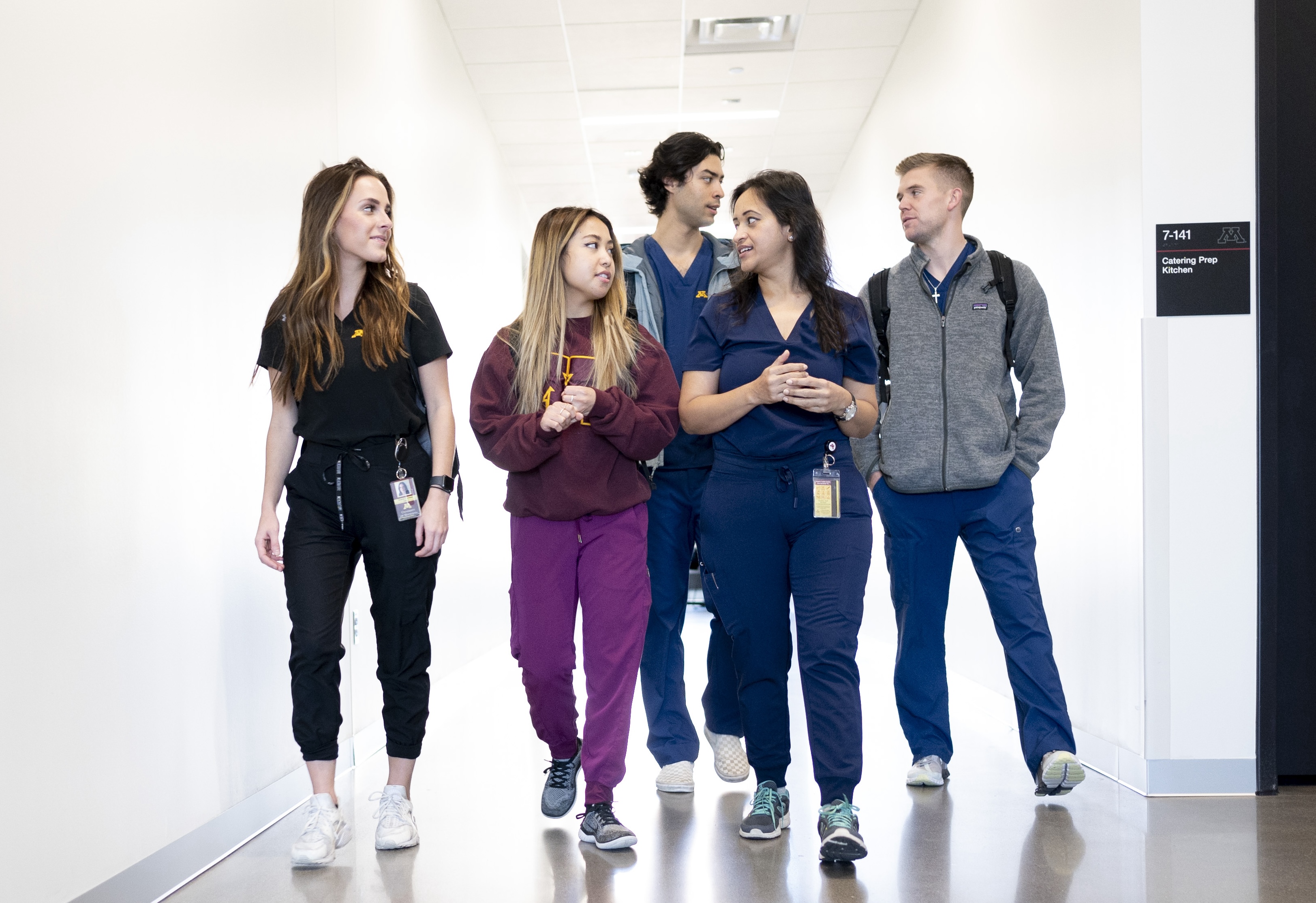 dental students walking down a hallway in scrubs and sweaters talking