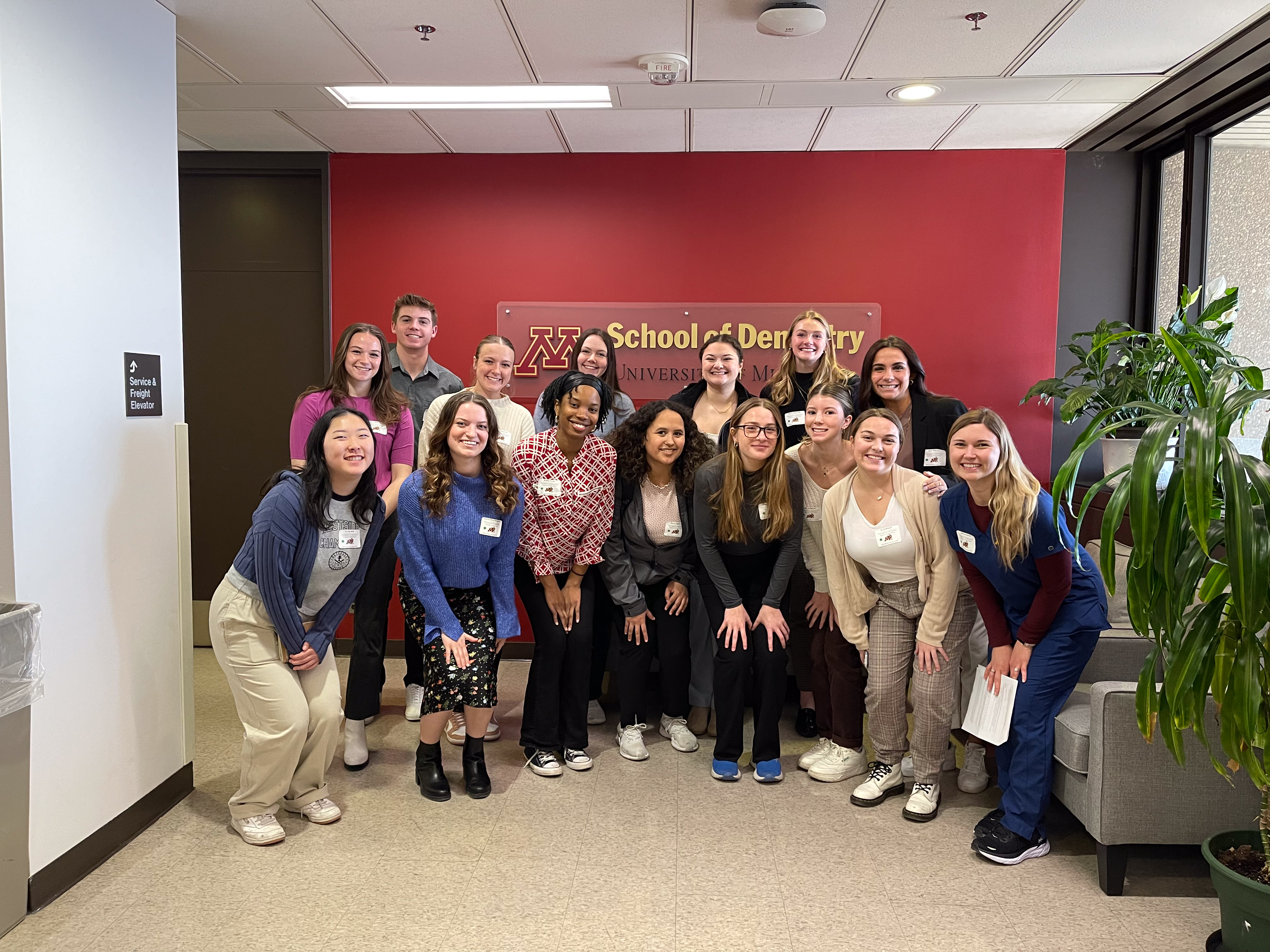 Attendees and students pose in front of the School of Dentistry sign