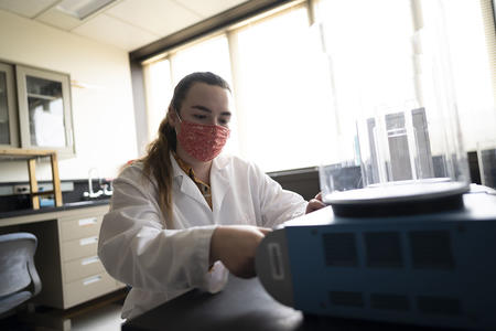 A woman wearing a mask using a dental machine