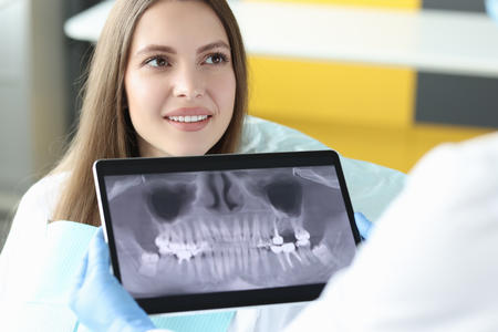 dental office with assistant viewing dental radiographs during a patient appointment