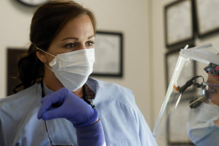 A dentist listens to a dental student in clinic