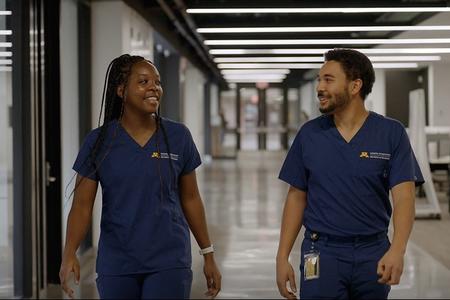 Two DDS students smile and walk down a hallway