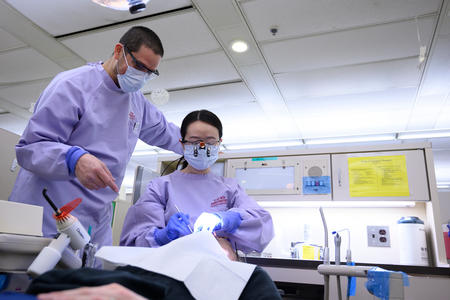 Two DDS students work on a patient together
