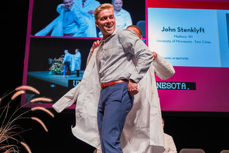 Student receives their white coat on stage