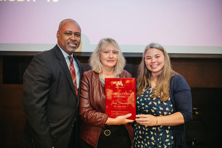 Dean Keith Mays, Judy Danielson, and Shivan Nelson pose, with Judy Danielson holding a plaque