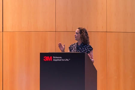 Kristin Artinger, PhD, speaks from a podium at 3M
