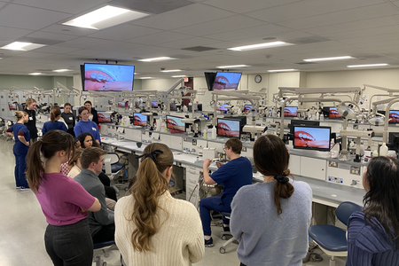 Attendees watch a dental student work in preclinic