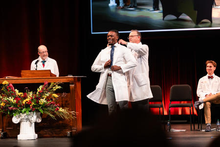 Tyrus Hayes smiles as he puts his white coat on onstage