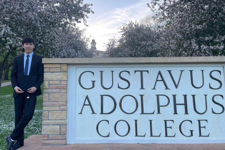 Mushtaq Wahidy next to Gustavus Adolphus College Sign