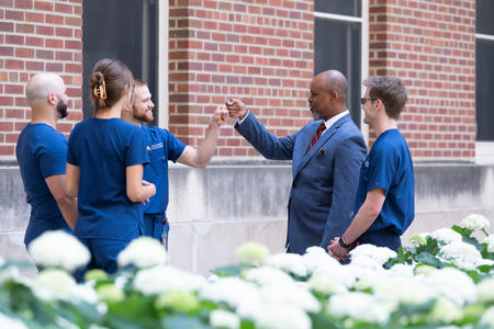 DDS students and Dean Keith Mays in the courtyard garden with a fist bump