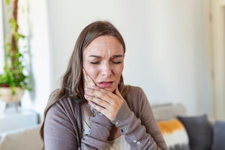 Woman holding jaw in pain.