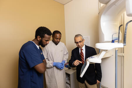 Mansur Ahmad shows two students how a CBCT works 