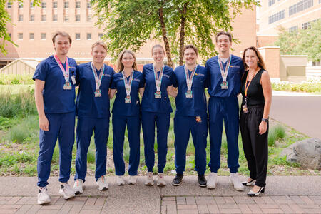 Marathon finishers pose in their scrubs with their metals