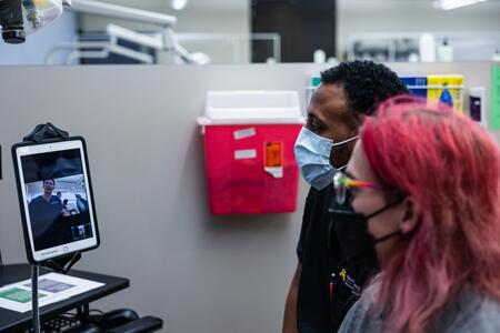 Student and standardized patient talk via tablet with a dental student 