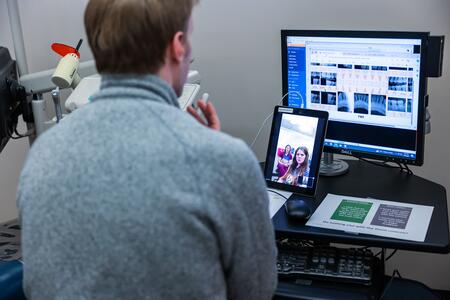A DDS student engages in a teledentistry simulation, with a patient and a dental hygiene student on a tablet