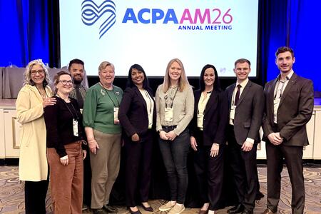 Members of the Cleft and Craniofacial Clinic pose in front of an APCA sign