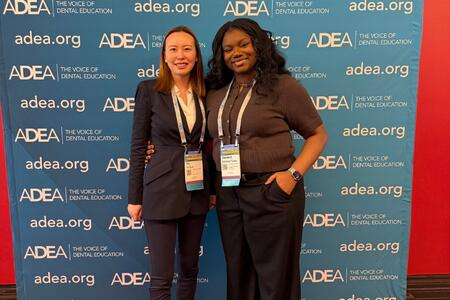 Sun and Taiwo pose in front of an ADEA banner at the annual meeting