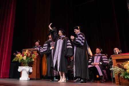 DDS student waves and smiles as she receives her doctoral hood