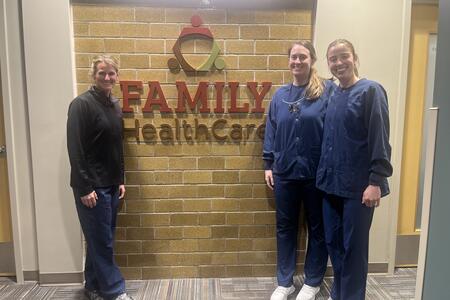 Jackie Nord and two DDS students pose in front of the Family HealthCare sign