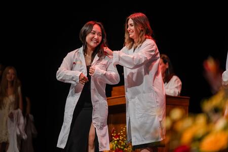 Student smiles and receives their white coat at the White Coat Ceremony