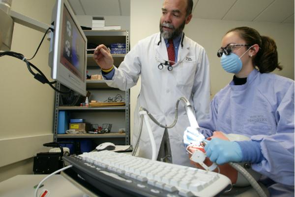 Student working on realistic practice dental dummy with help of instructor