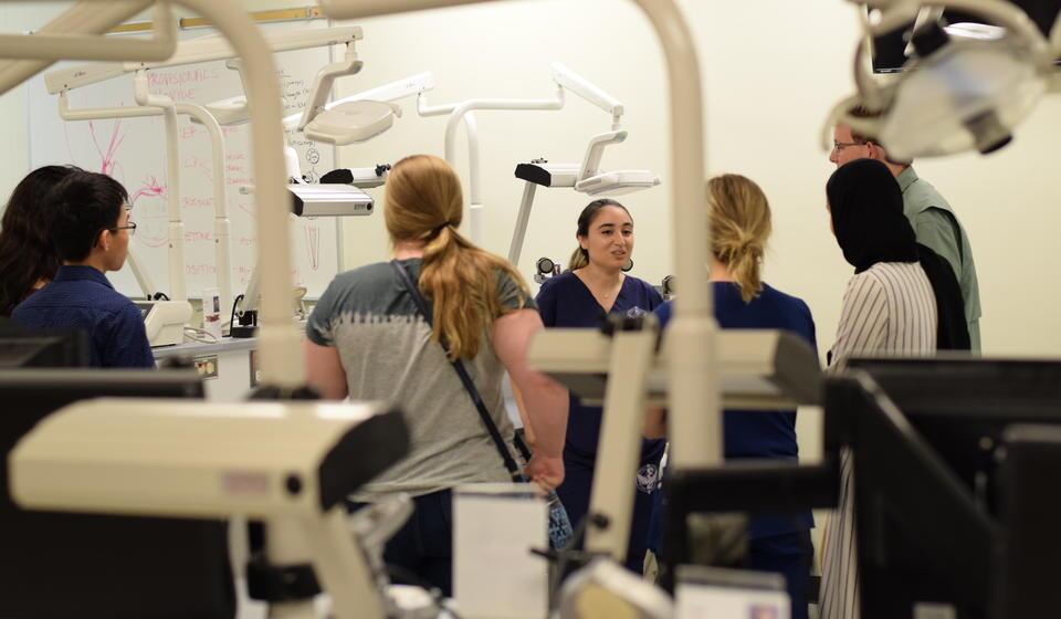 A group of women wearing scrubs talking amongst equipment