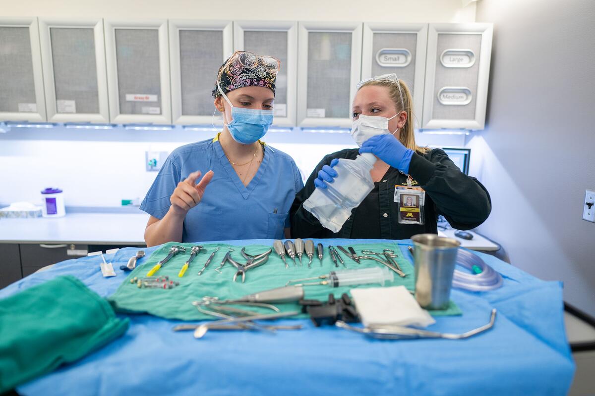 Two members of the oral and maxillofacial surgery team talk in front of a number of instruments in a clinic