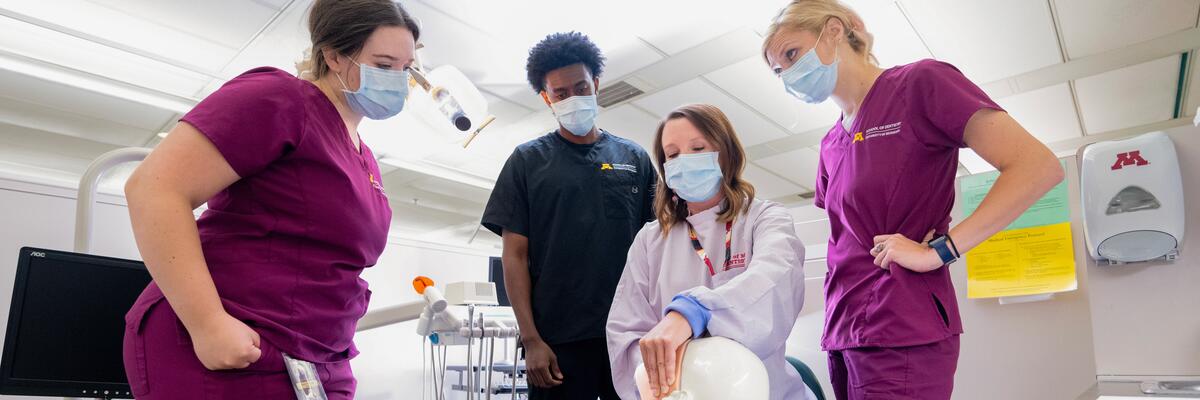 group of dental hygiene students learning from an instructor on a model patient