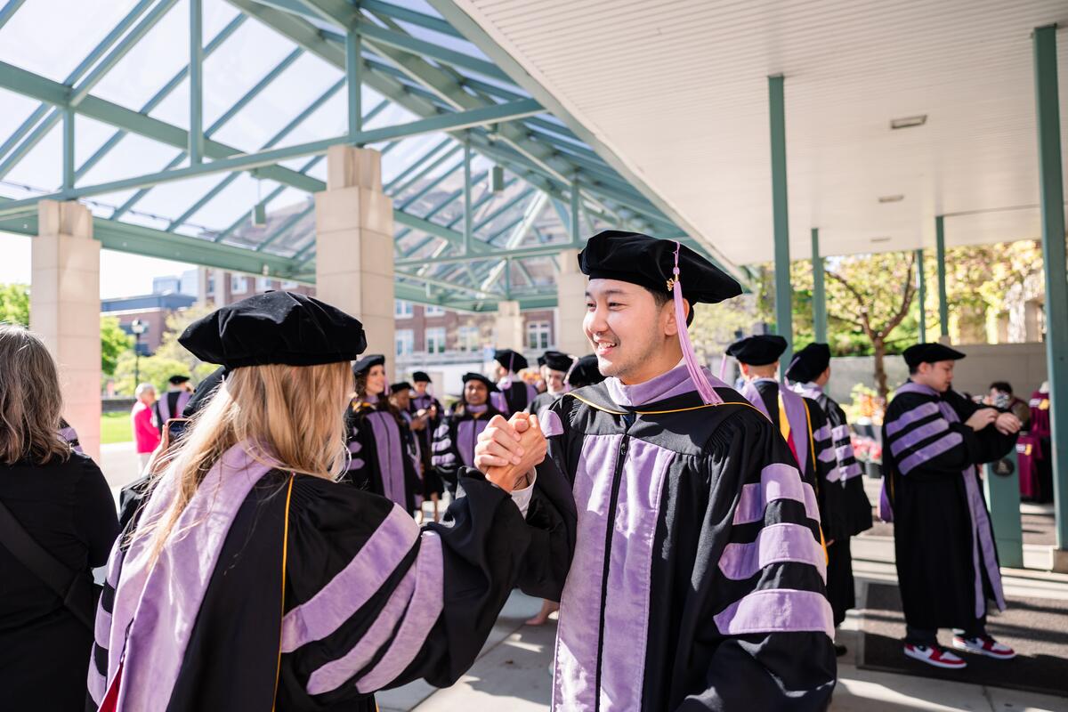 Two graduates embrace hands