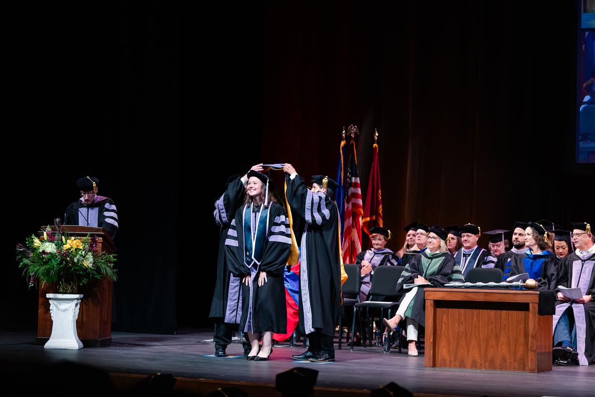 A graduate is hooded onstage