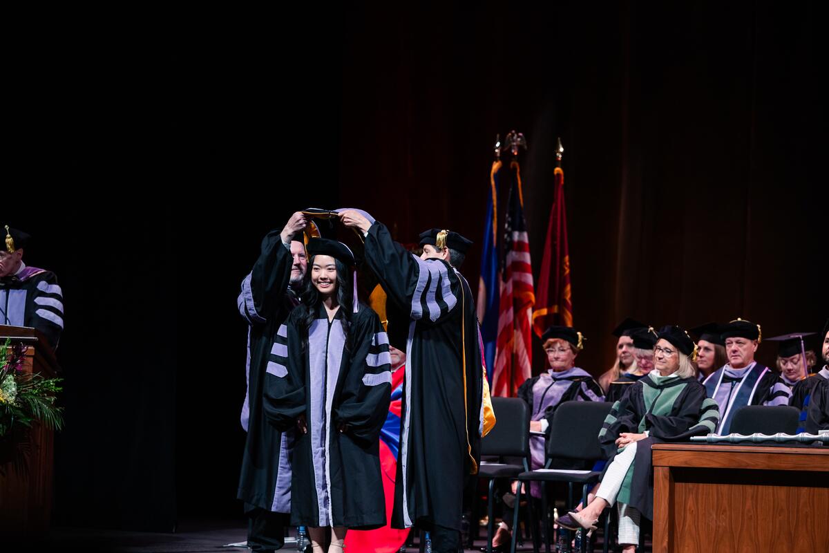 A graduate is hooded onstage