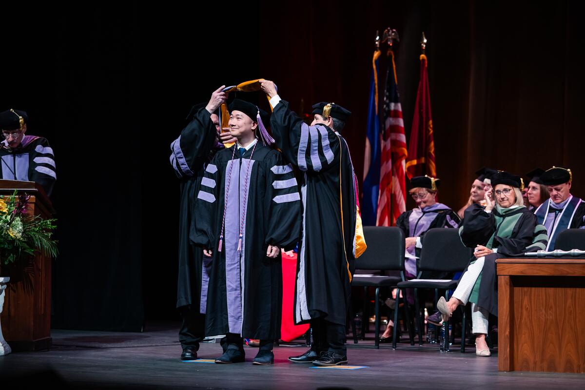 A graduate is hooded onstage
