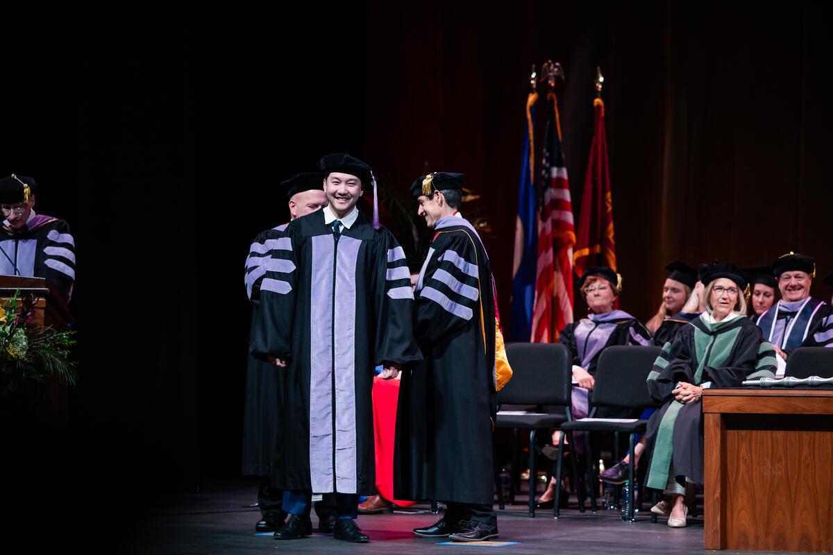 A graduate is hooded onstage