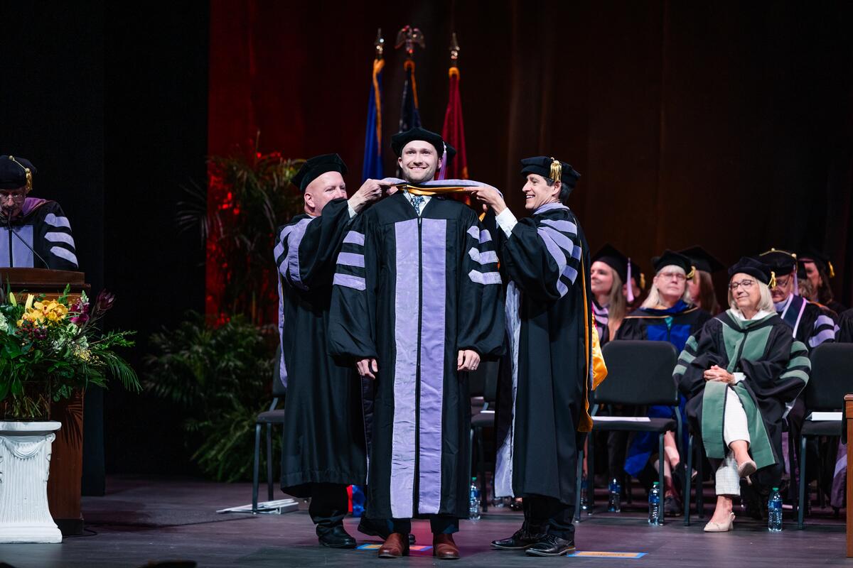 A graduate is hooded onstage