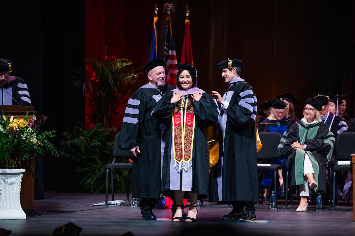 A graduate is hooded onstage