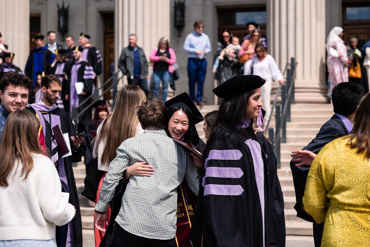 A graduate hugs a family member outside
