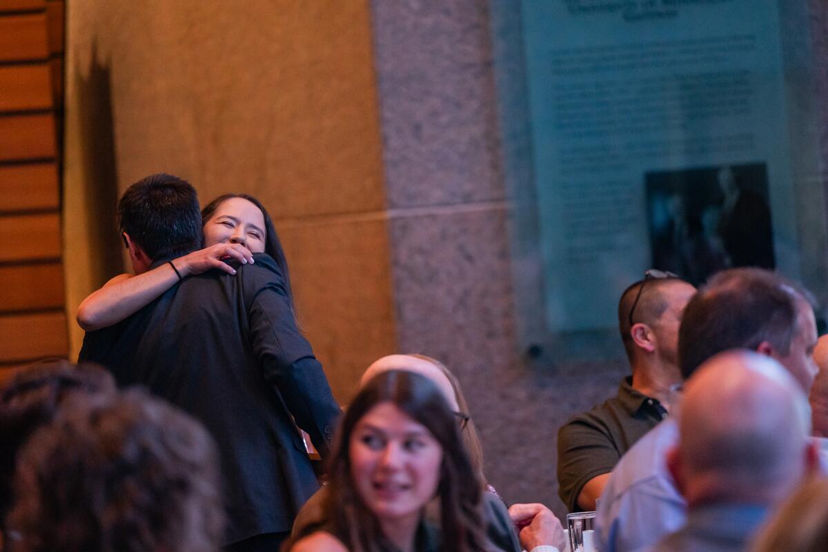 Class officer smiles and hugs Faculty of the Year awardee
