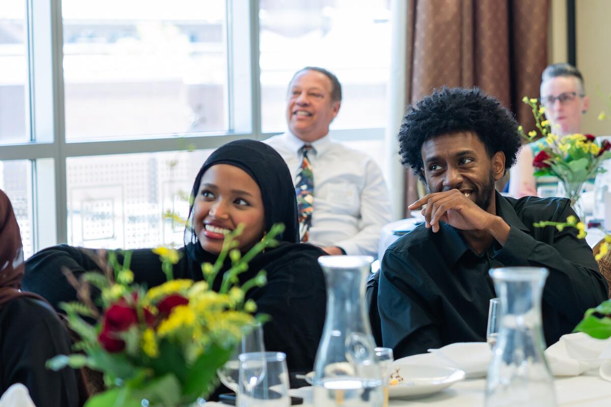 Michael Abebe and Mulki Hassan smile while watching a slideshow presentation