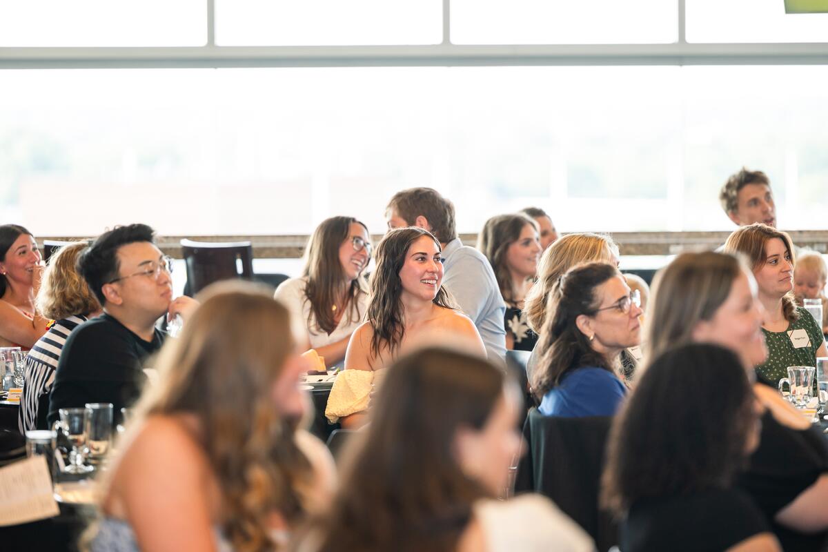 Attendees smile and watch a presentation