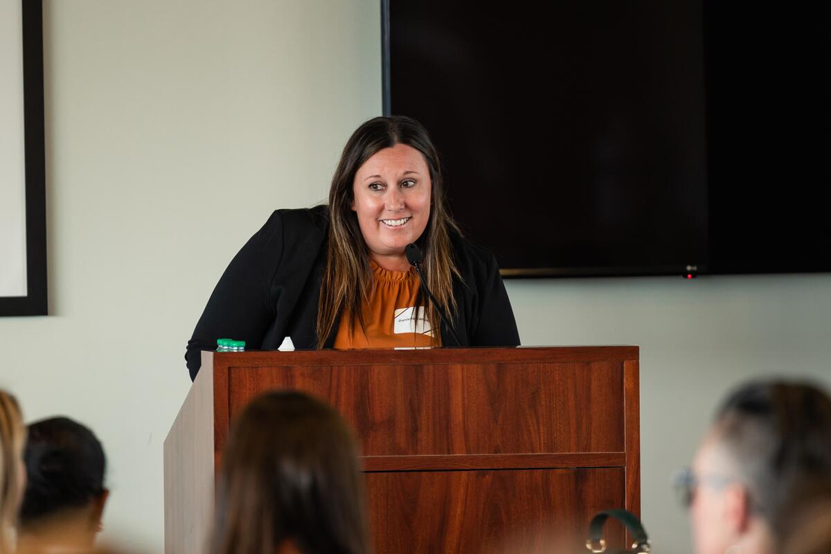 Presenter smiles from behind the podium as she announces an award