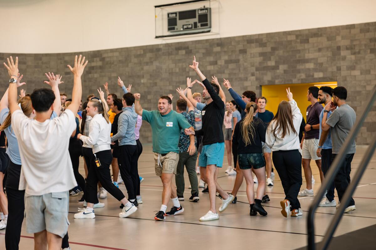 Learners raise their arms and walk around to participate in teambuilding activities
