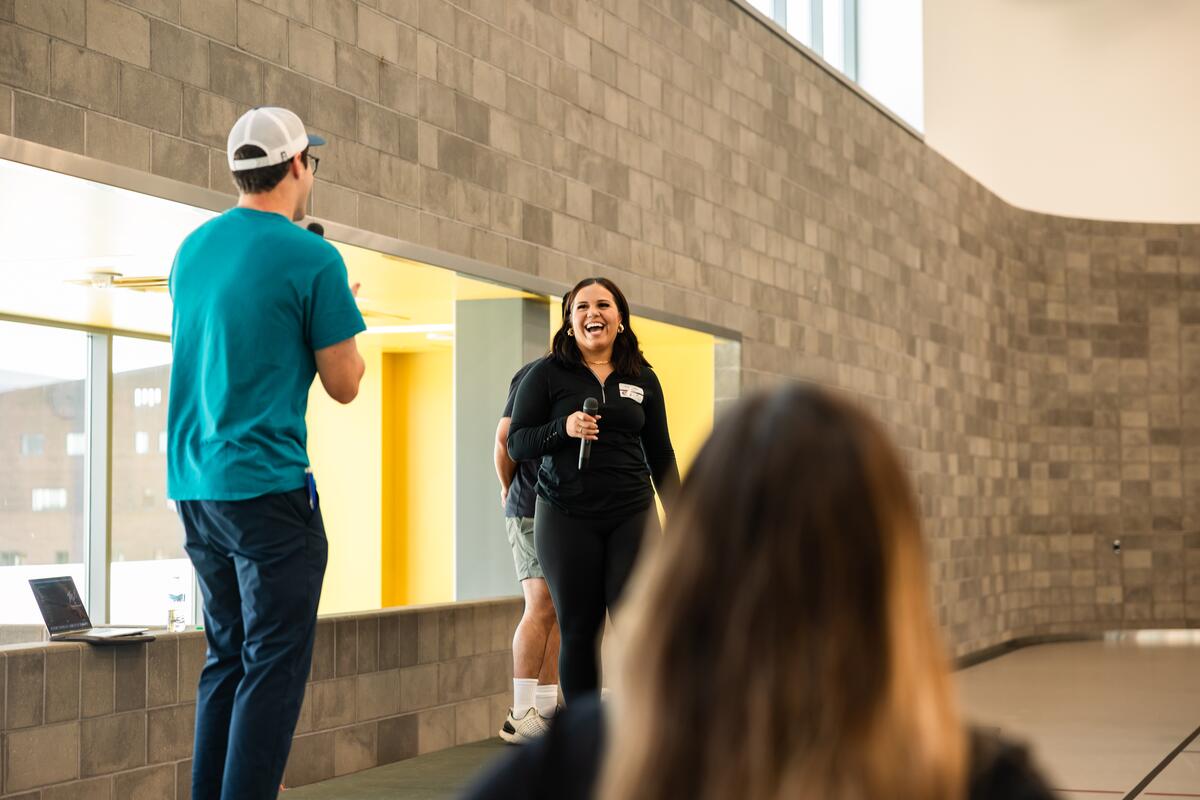A new student speaks from a microphone and smiles during teambuilding activities