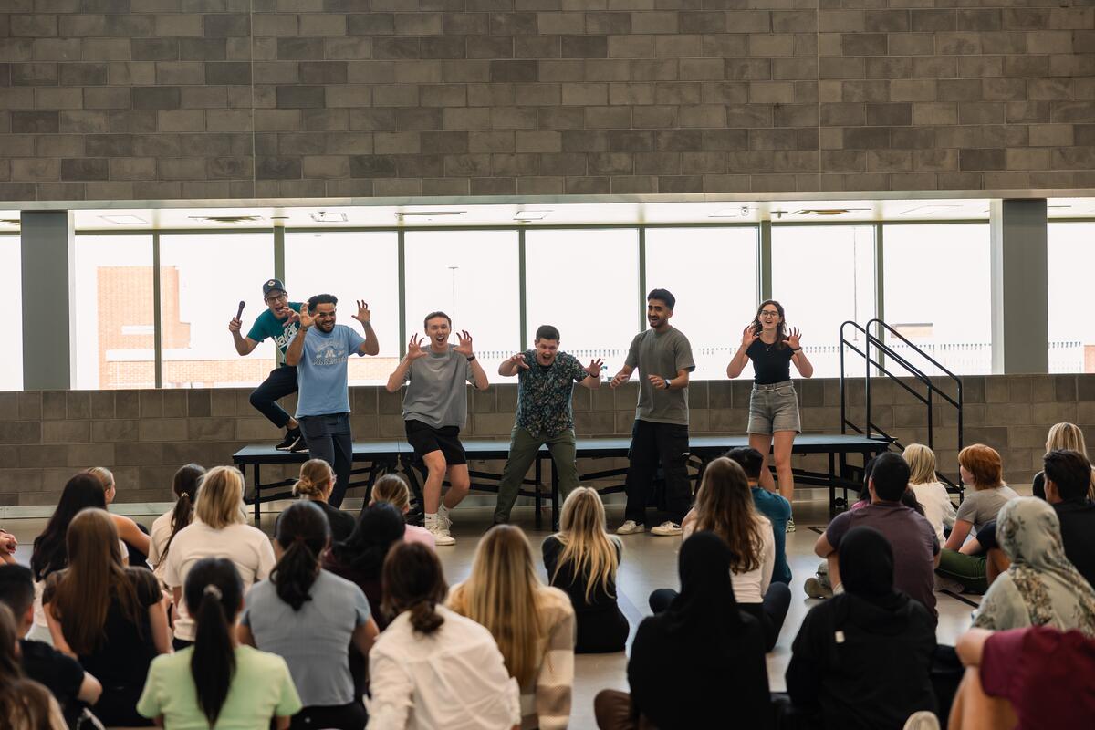 Five students pantomime as dinosaurs in front of their classmates for teambuilding activities