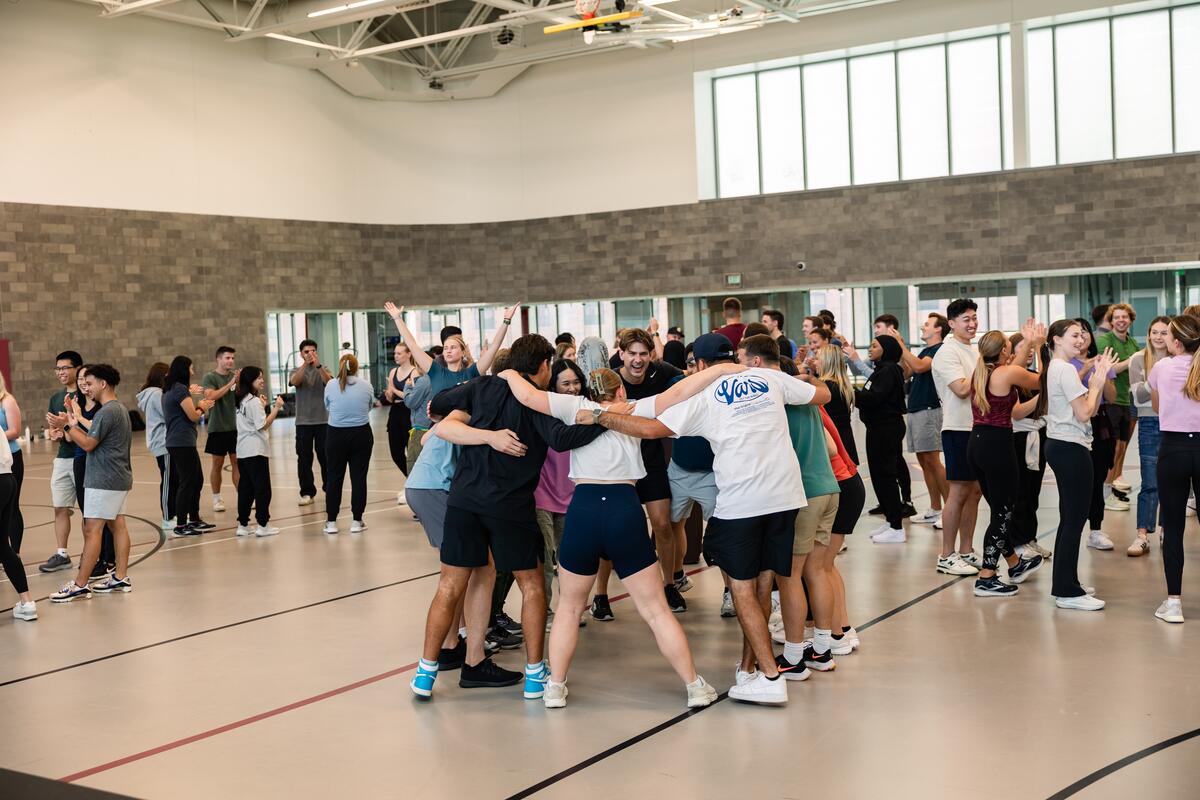 A group of students makes a team huddle during orientation teambuilding activities