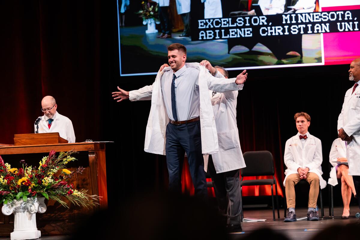 Student receives his white coat onstage