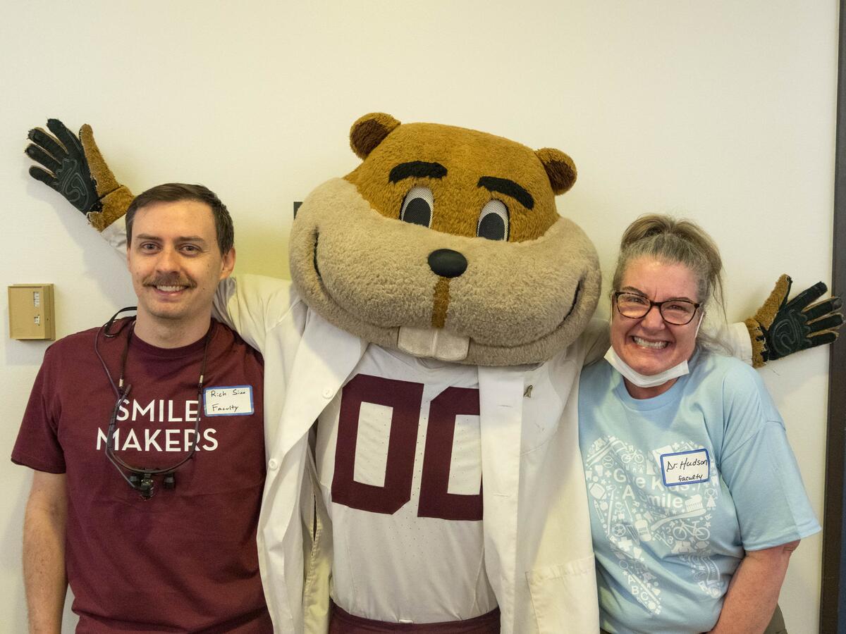 Goldy and faculty members smiling.