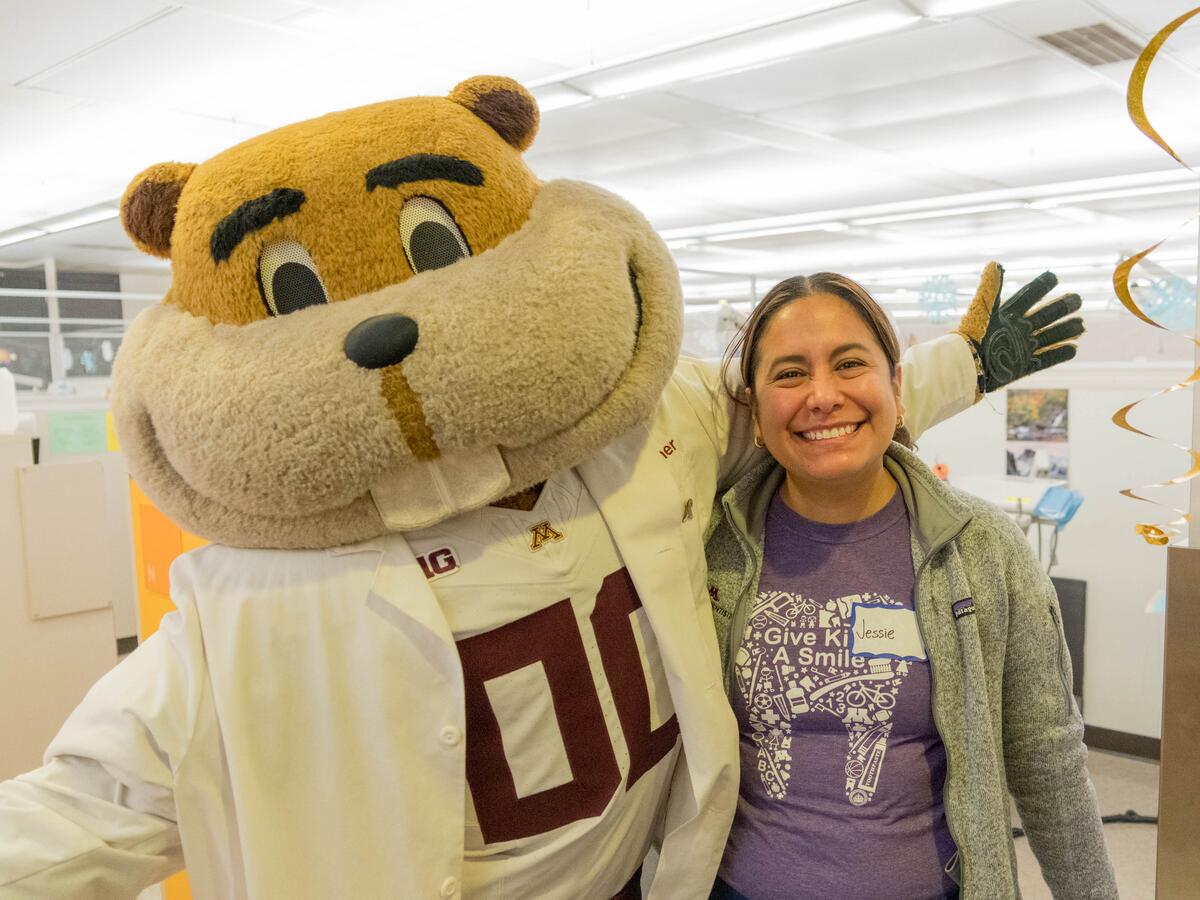Goldy and volunteer smiling at event.