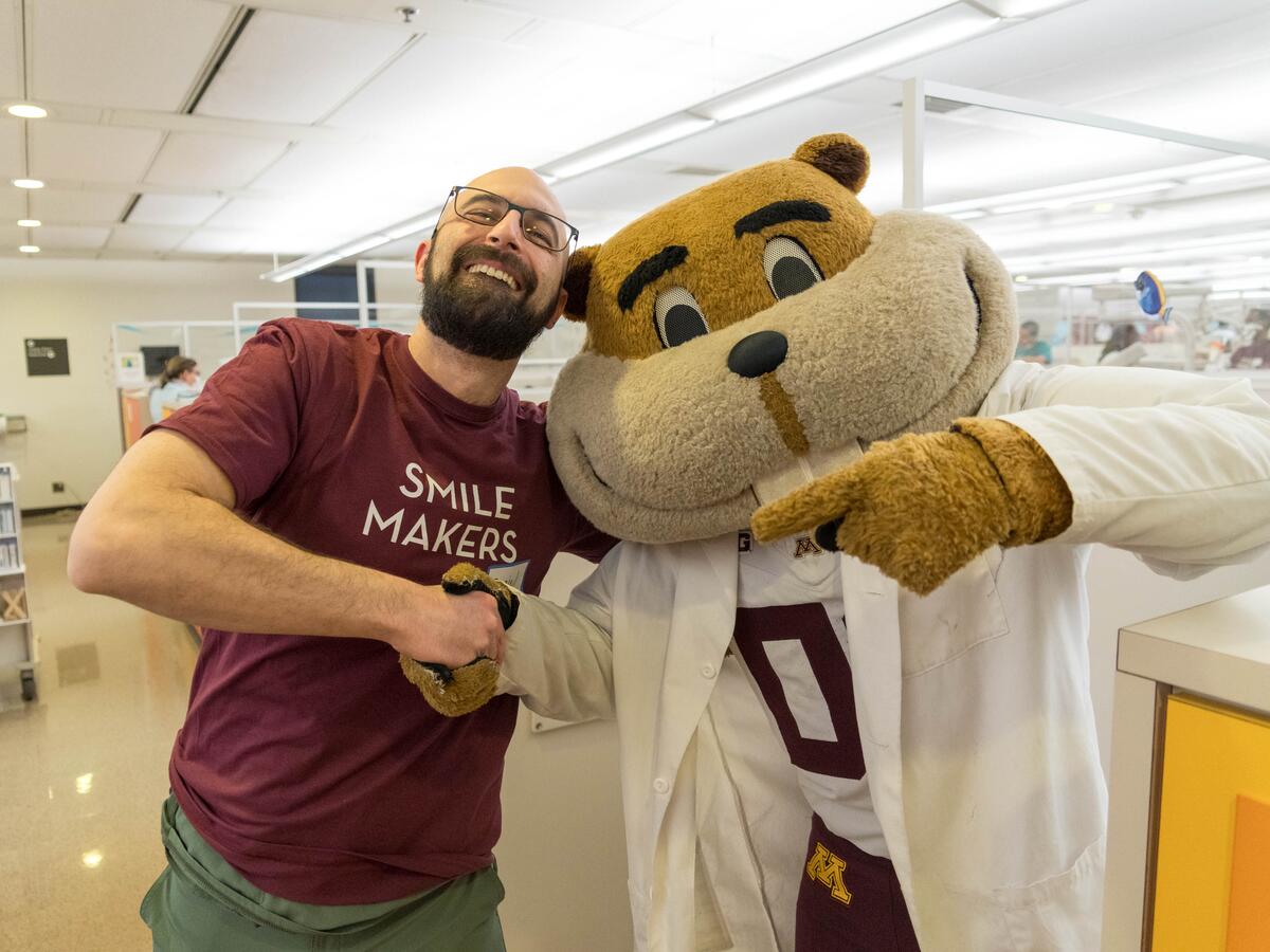 Goldy shaking hands with faculty member. 