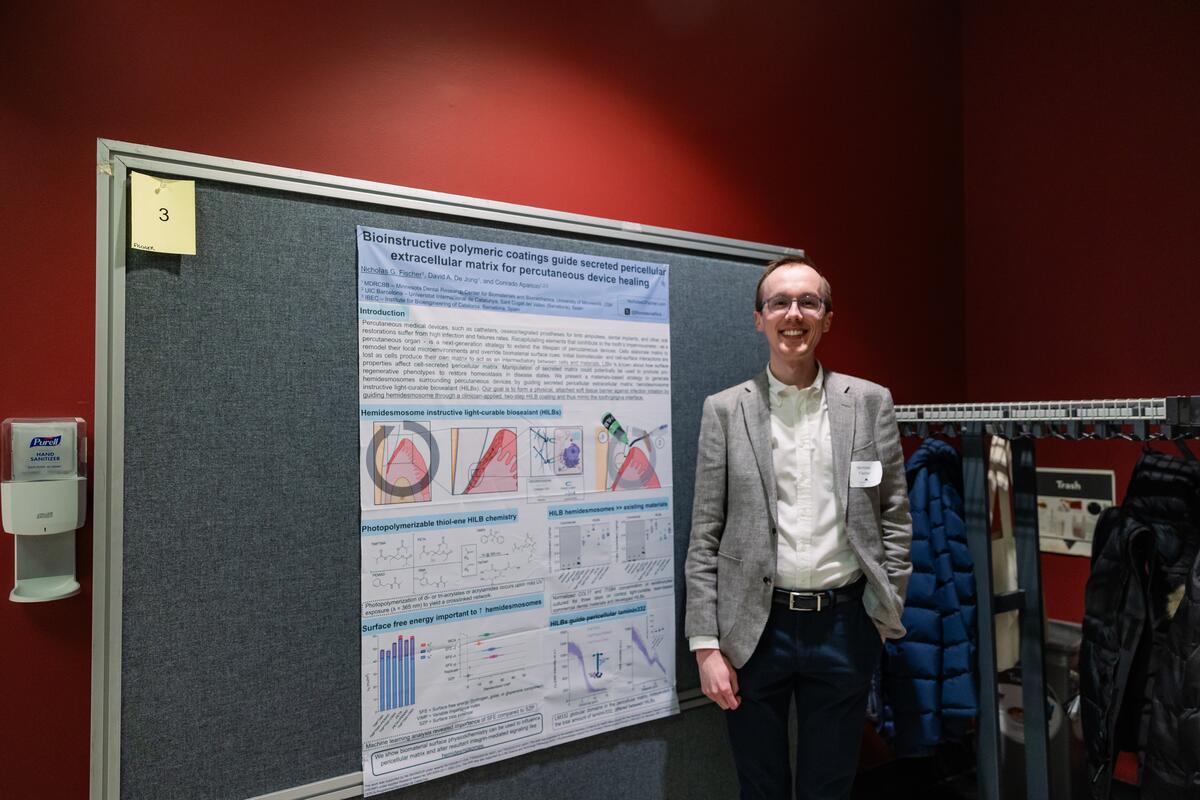 A student poses with his research poster